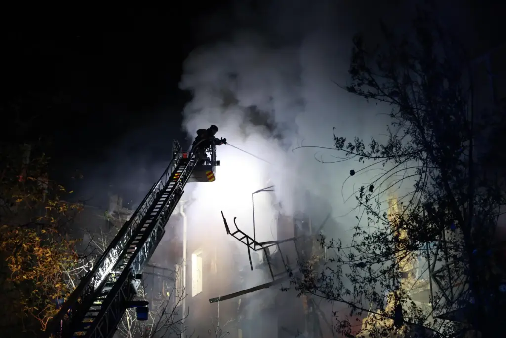 Rescue workers try to put out a fire of a...