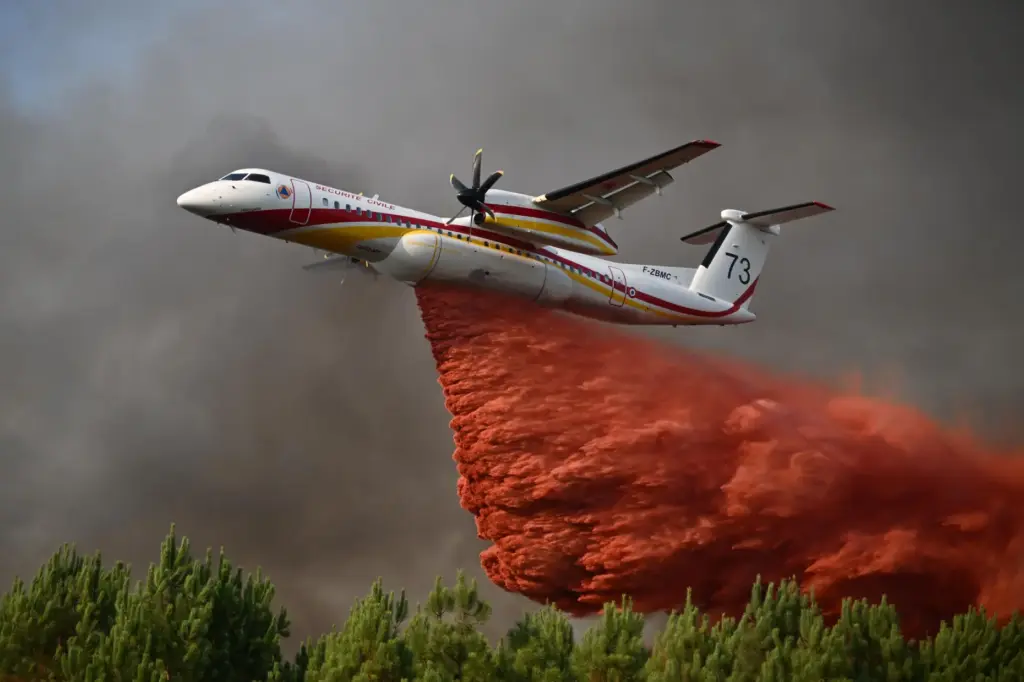 FILE – A plane releases fire retardant as it flies...