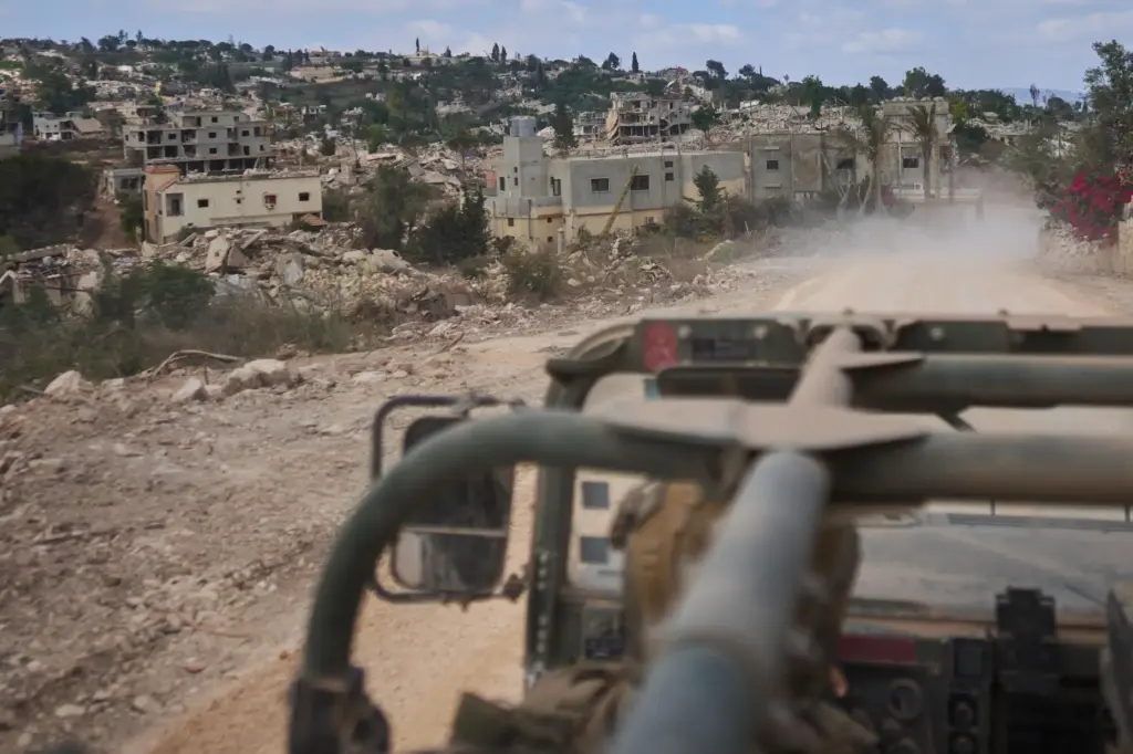 An Israeli soldier rides in a military vehicle past destroyed...