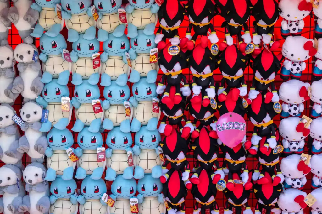 Stuffed animal prizes hang on a wall above a game...