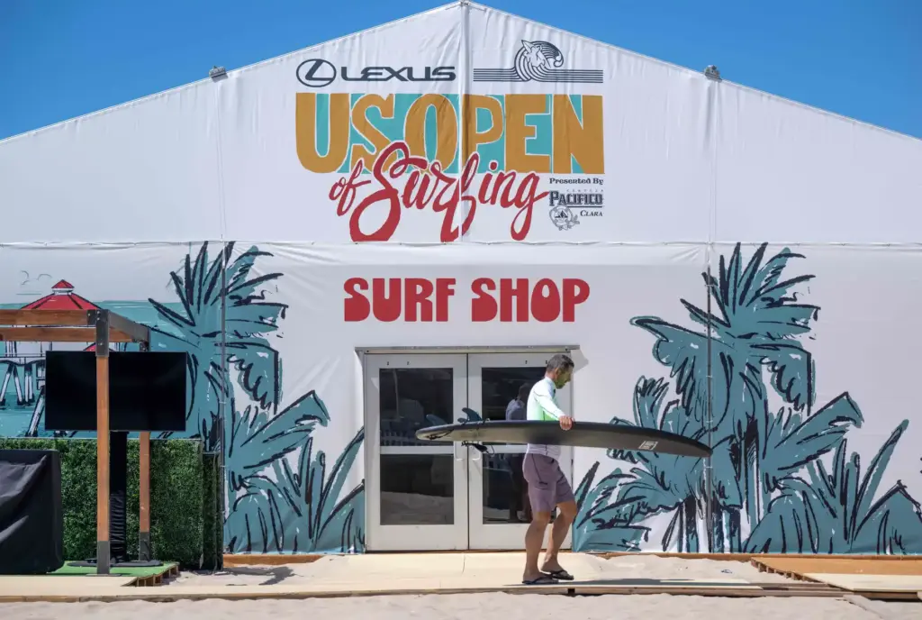 A surfer walks past a US Open of Surfing surf...