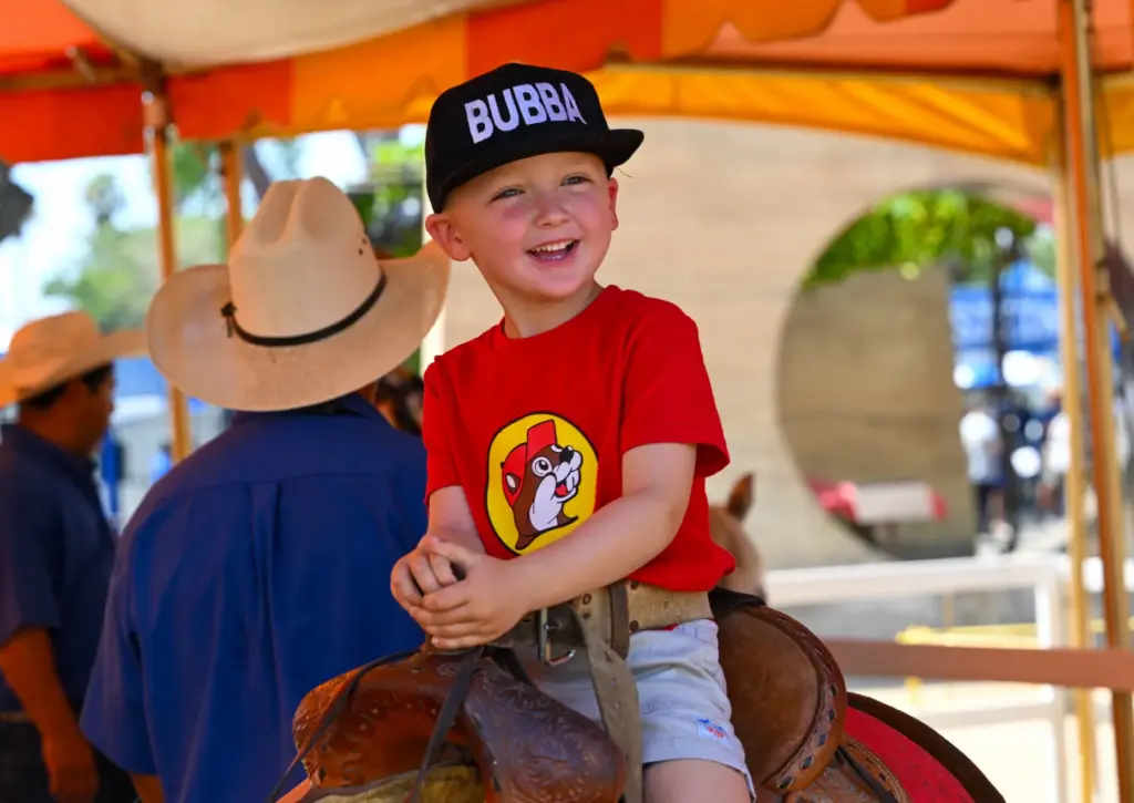 Tyler Henry, of Long Beach, rides a pony during opening...