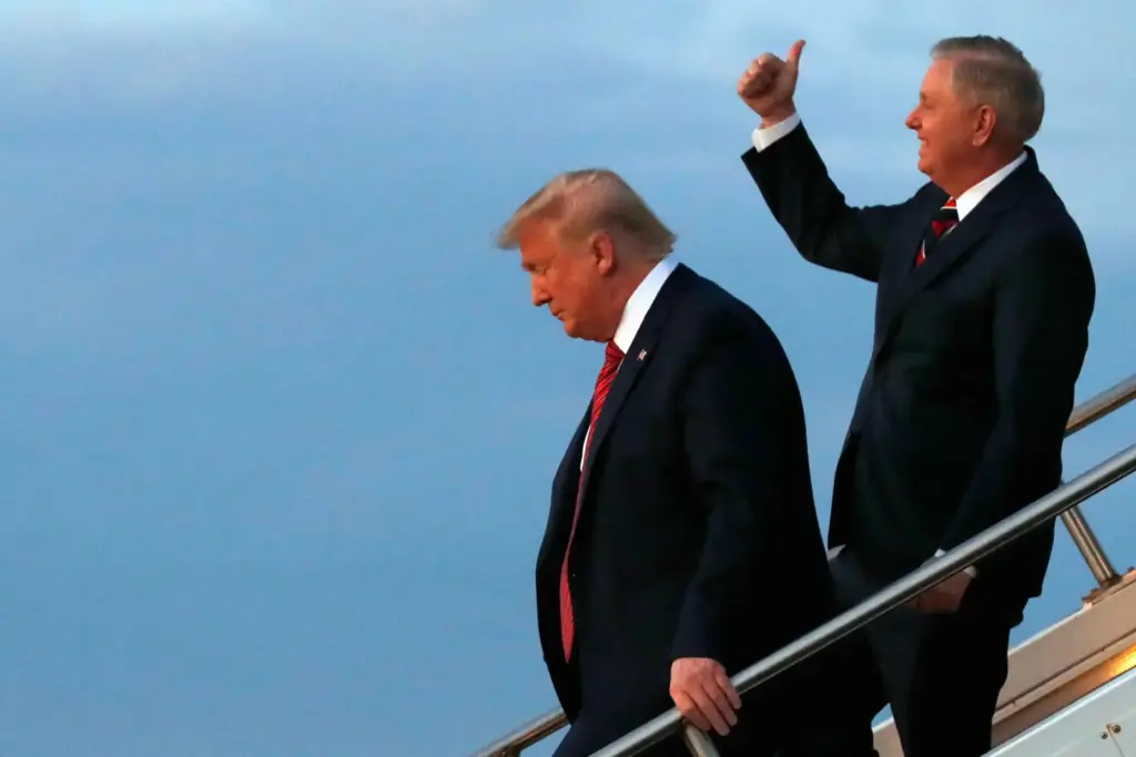 FILE – President Donald Trump, left, exits Air Force One...