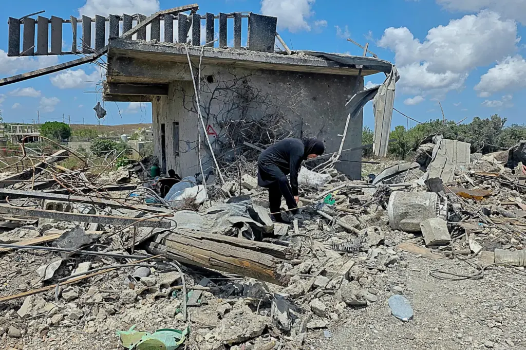 A Lebanese woman clears debris of her destroyed house in...