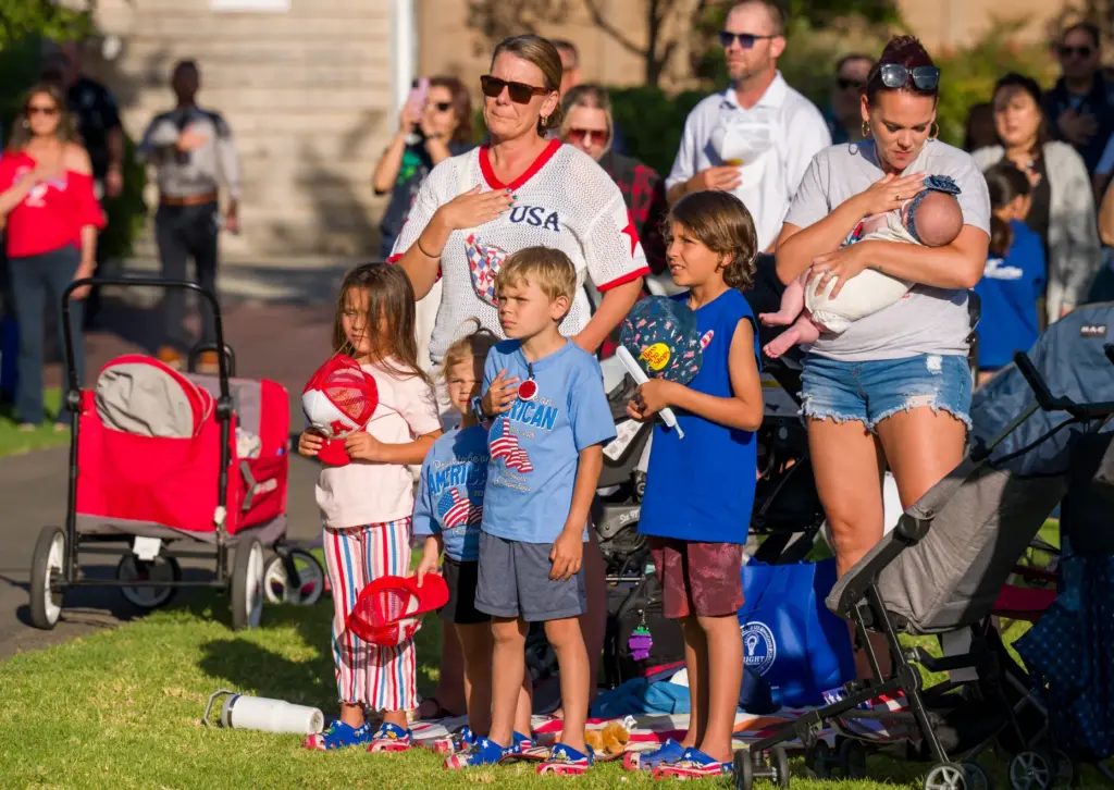 Families put their hands over their heart during a singing...