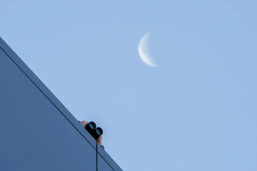 A law enforcement officer uses binoculars to watch from the roof of the Fourth District Courthouse.
