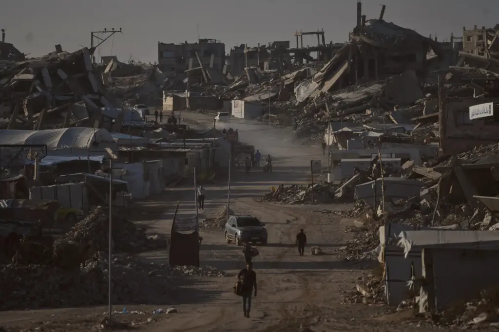Palestinians walk along a road surrounded by buildings destroyed in...