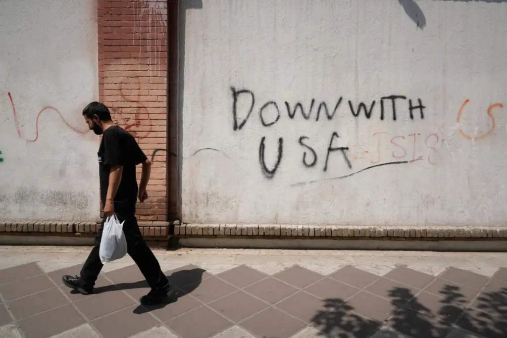 A man walks past anti-U.S. graffiti on the wall of...