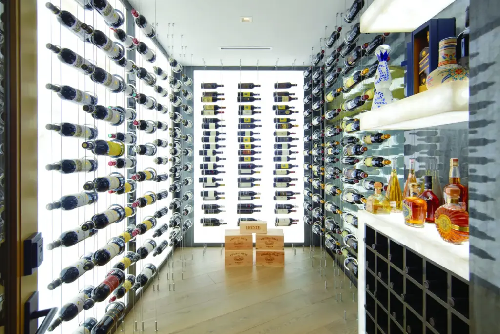 The wine room features floating bottle displays set against backlit...