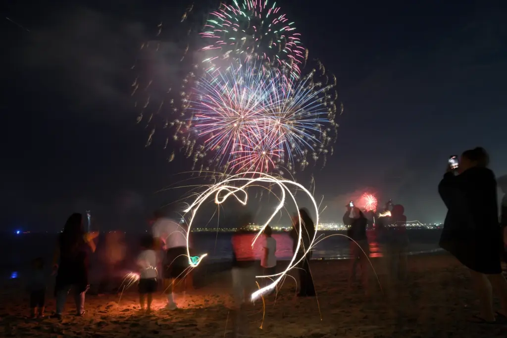 Children play with sparklers as simultaneous fireworks displays in Long...