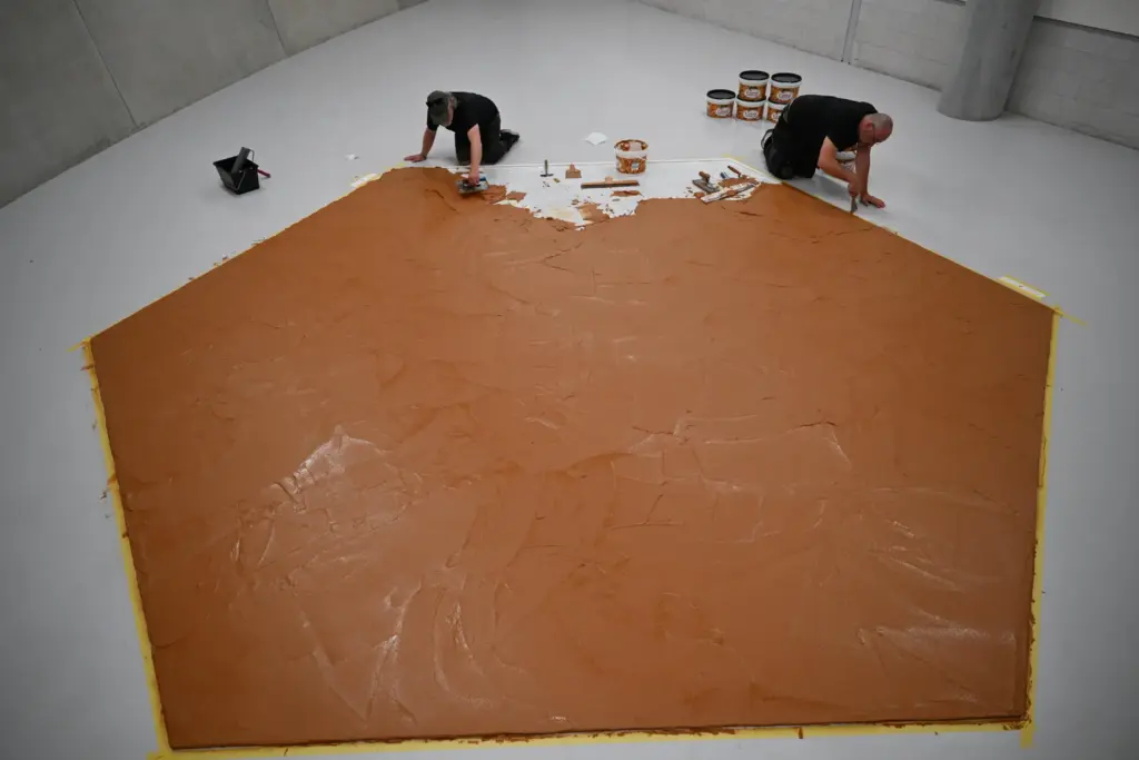 Workers spread peanut butter on a floor to re-create the 