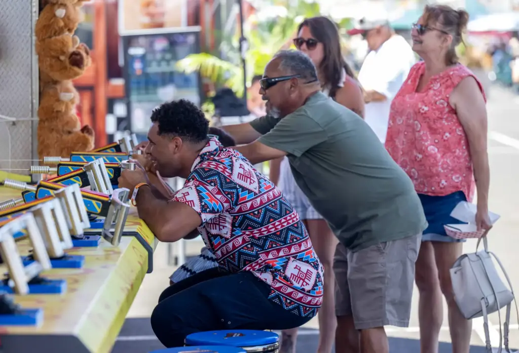 Fairgoers shoot water at targets as they play a water...