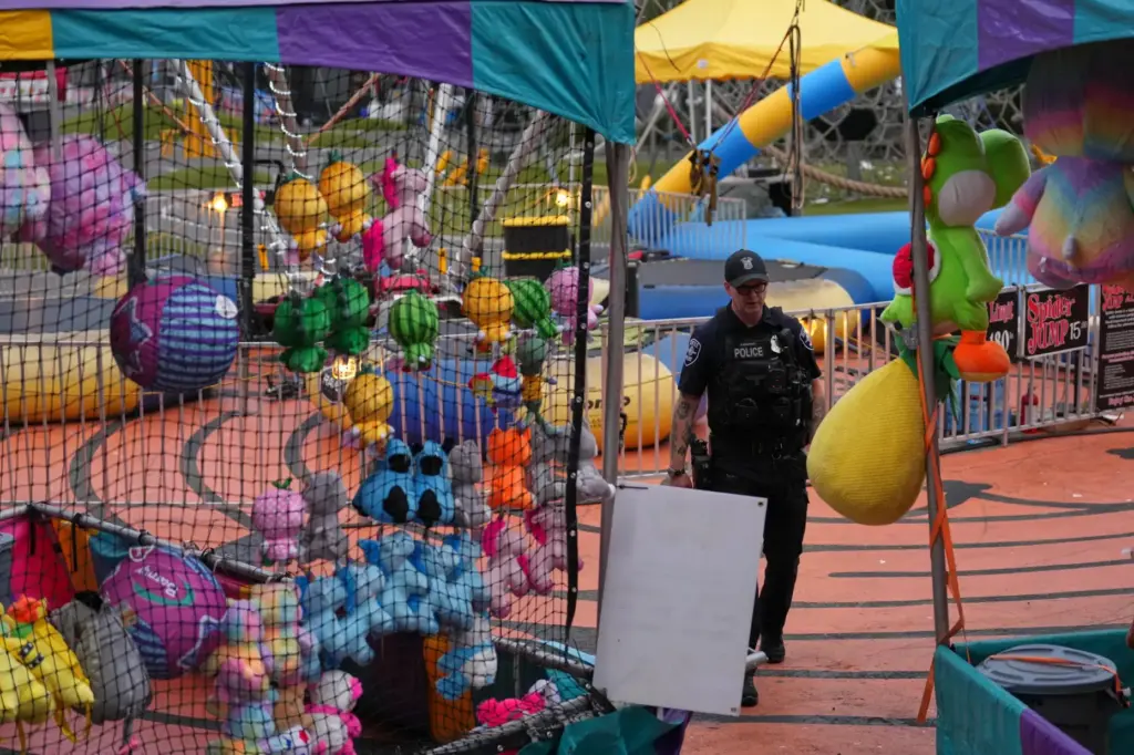 A Seattle Police officer walks through tents with colorful toys at the scene of a shooting.
