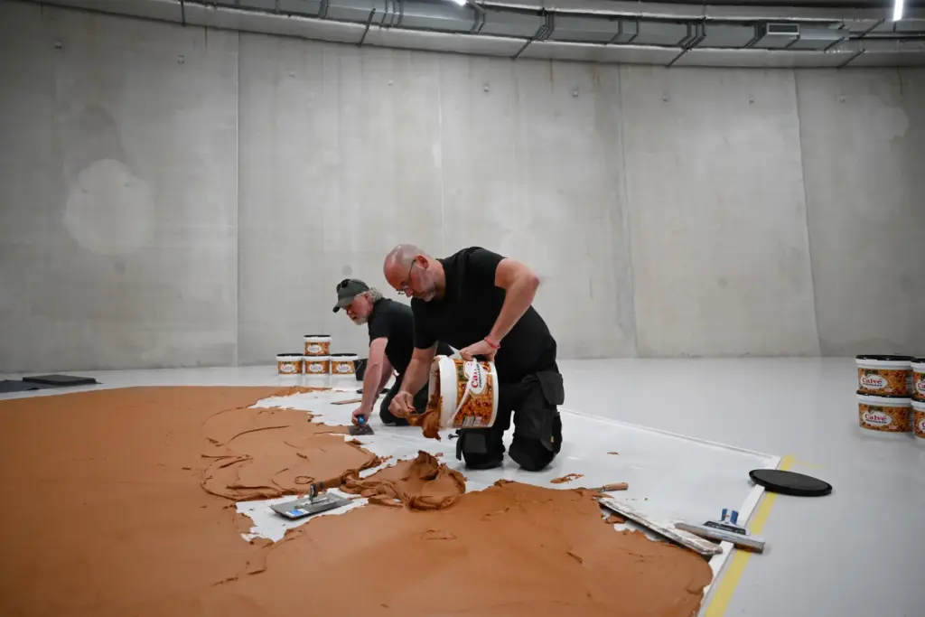 Workers spread peanut butter on a floor to re-create the 
