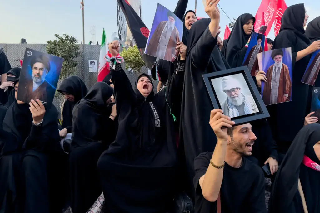 Mourners hold a portrait of Mojtaba Khamenei and Ali Khamenei.