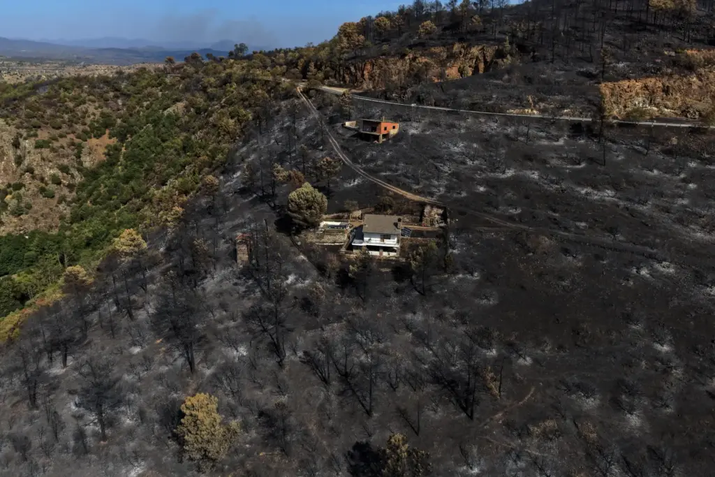 FILE – An area scorched by a wildfire surrounds structures...