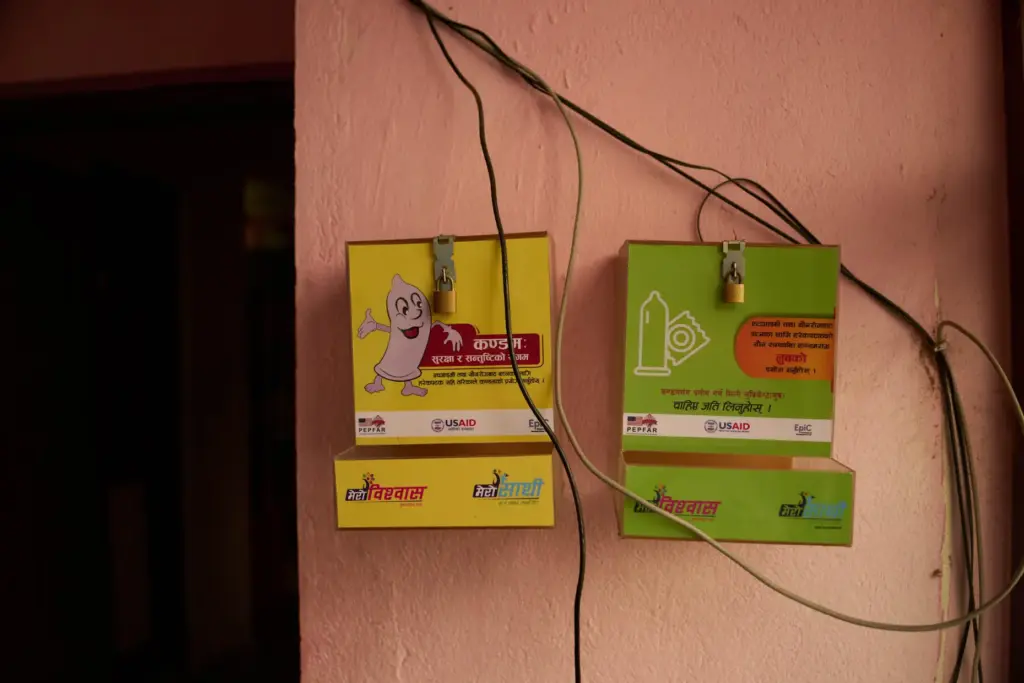 An empty condom dispenser hangs outside an office in Kathmandu,...