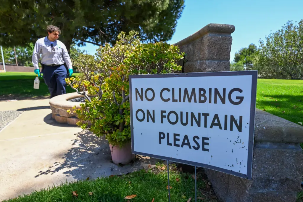 Vector Control Inspector Kevin Isunza looks for mosquitoes in fountain...