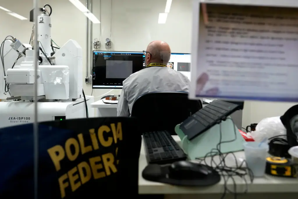 A federal police forensic expert works at an electron microscope analyzing gold samples.