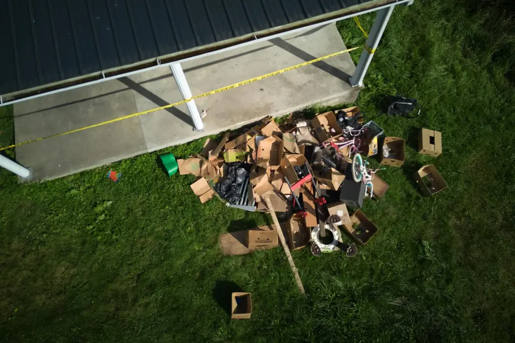 Debris is strewn on the front lawn of a home...