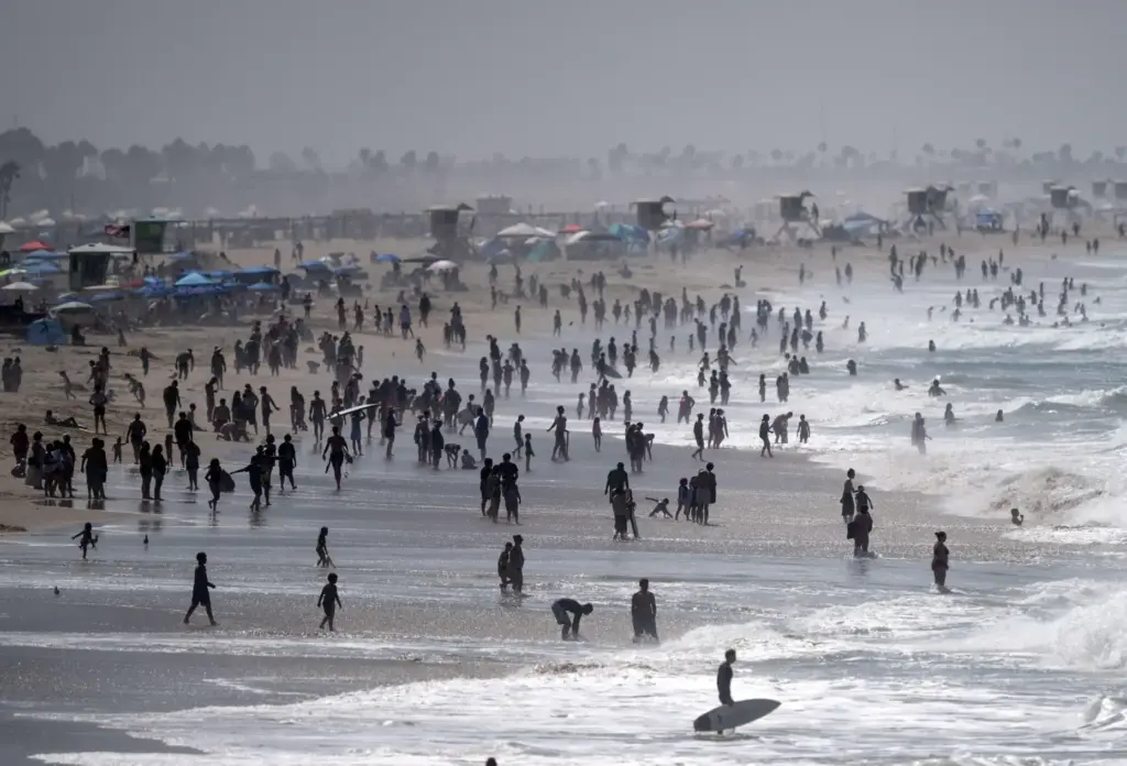 Thousands of beachgoers hang out on the sand and in...