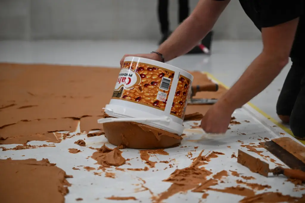 Workers spread peanut butter on a floor to re-create the 