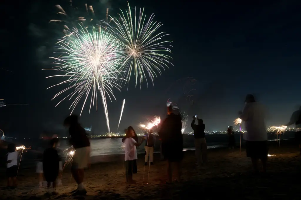 Children play with sparklers as simultaneous fireworks displays in Long...