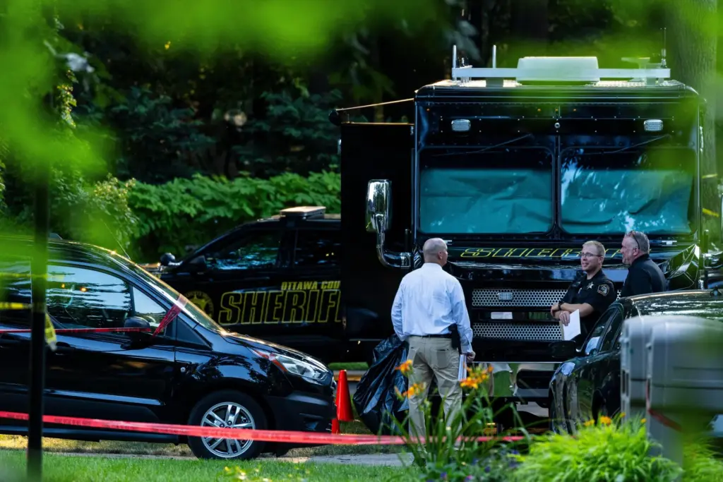 Law enforcement officials investigate the scene of a fatal house...