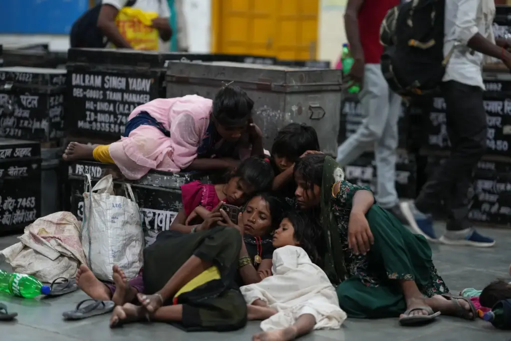 Children gather around a mobile phone as local residents rest...
