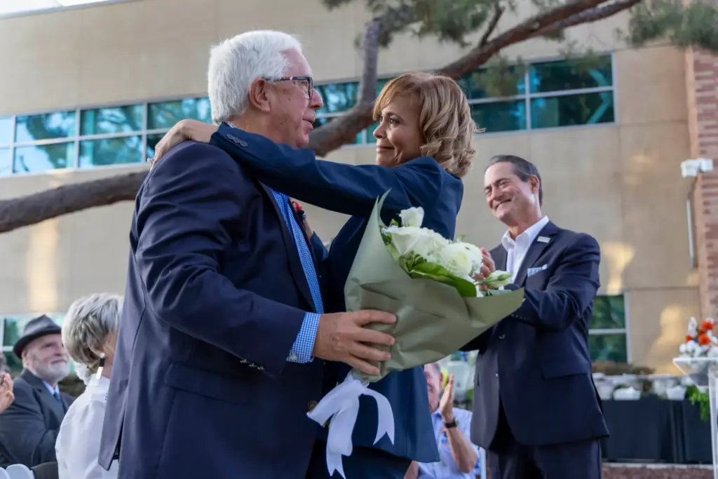Paul Paulsen (left) hugs Cal State Fullerton Vice President Phenicia...
