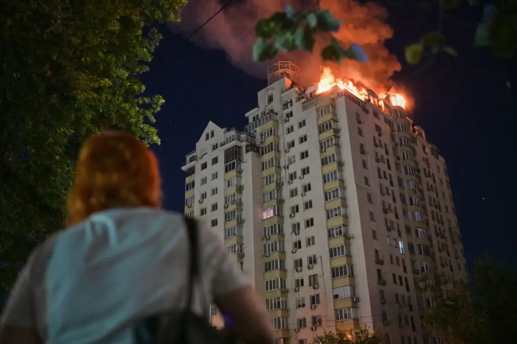 A woman looks at an apartment building burning after a...