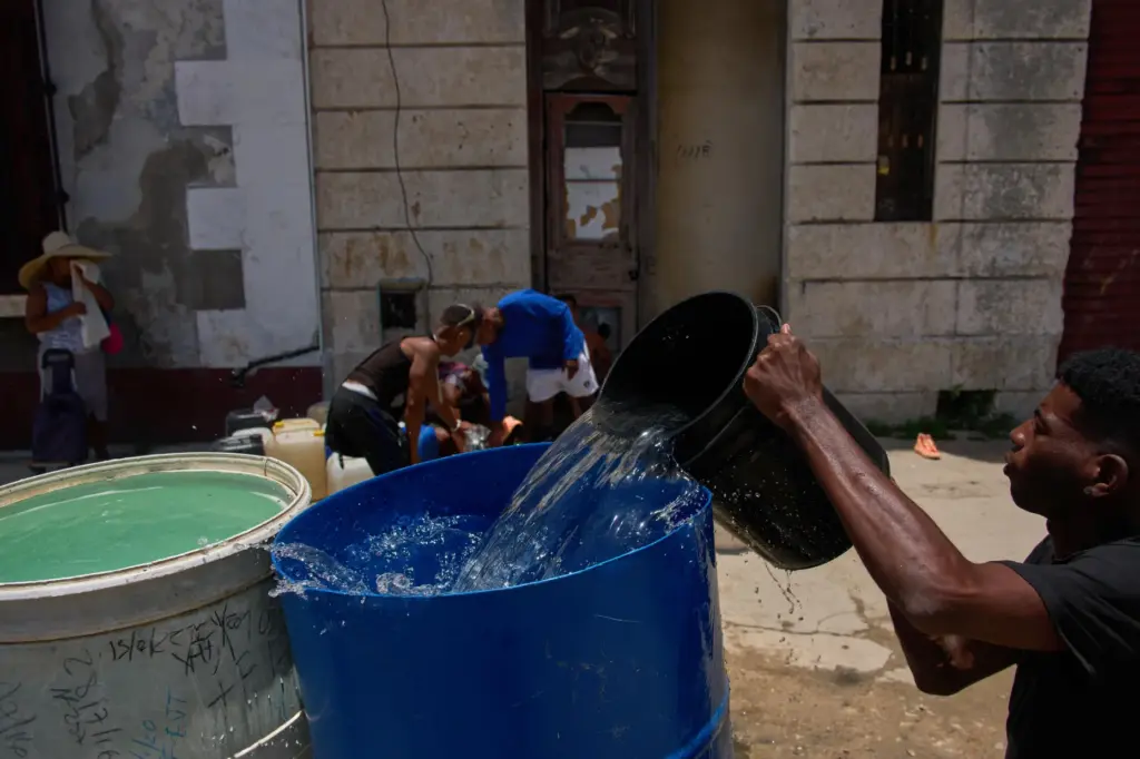People collect water from a street tap during a blackout...