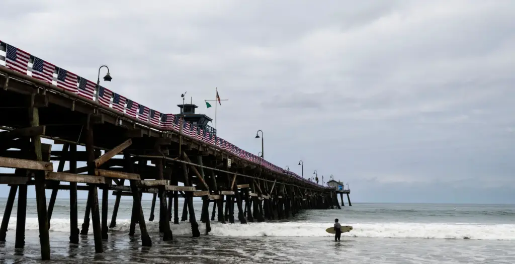 A surfer heads into the water at the pier in...