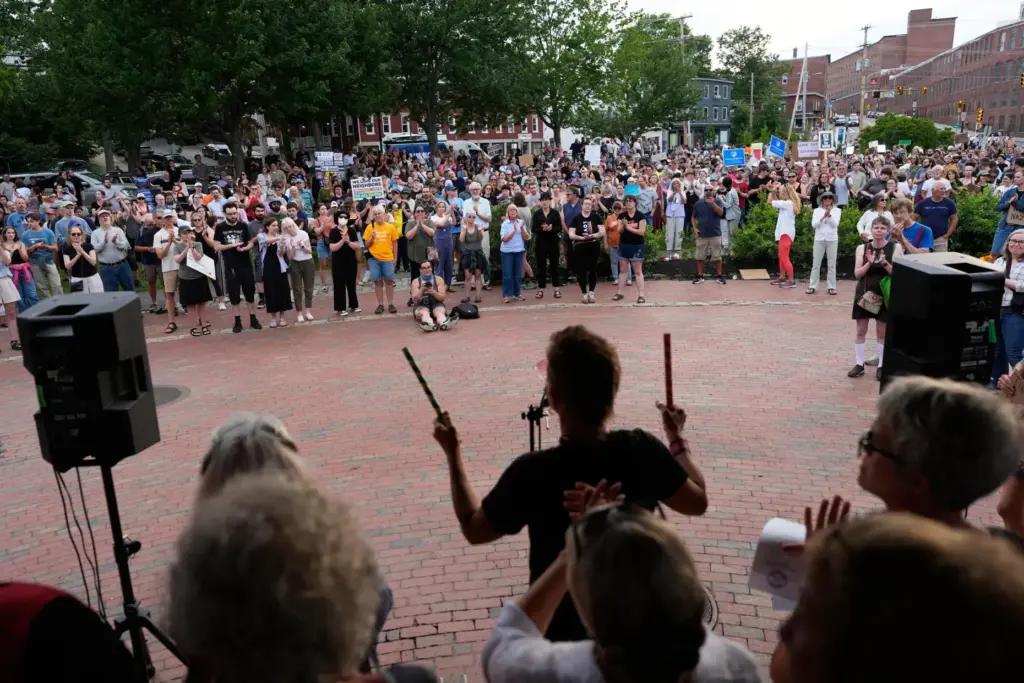 Attendees stand during a vigil after a man was shot and killed by ICE.