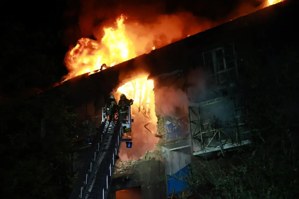 Rescue workers try to put out a fire of a...