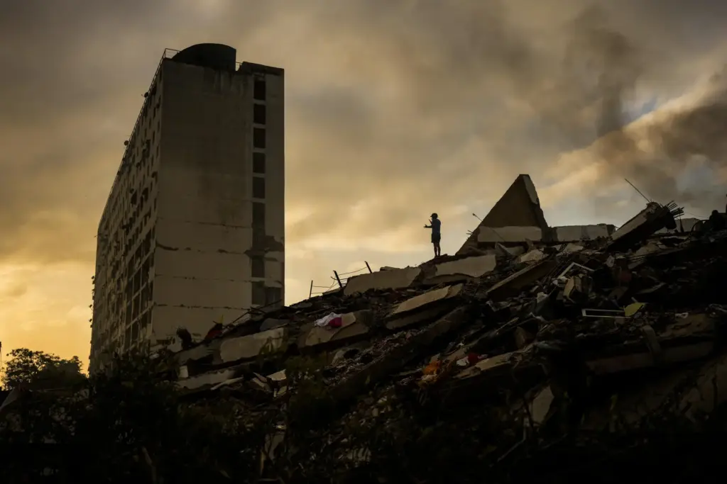 A man stands atop a mountain of rubble three days after twin earthquakes struck.