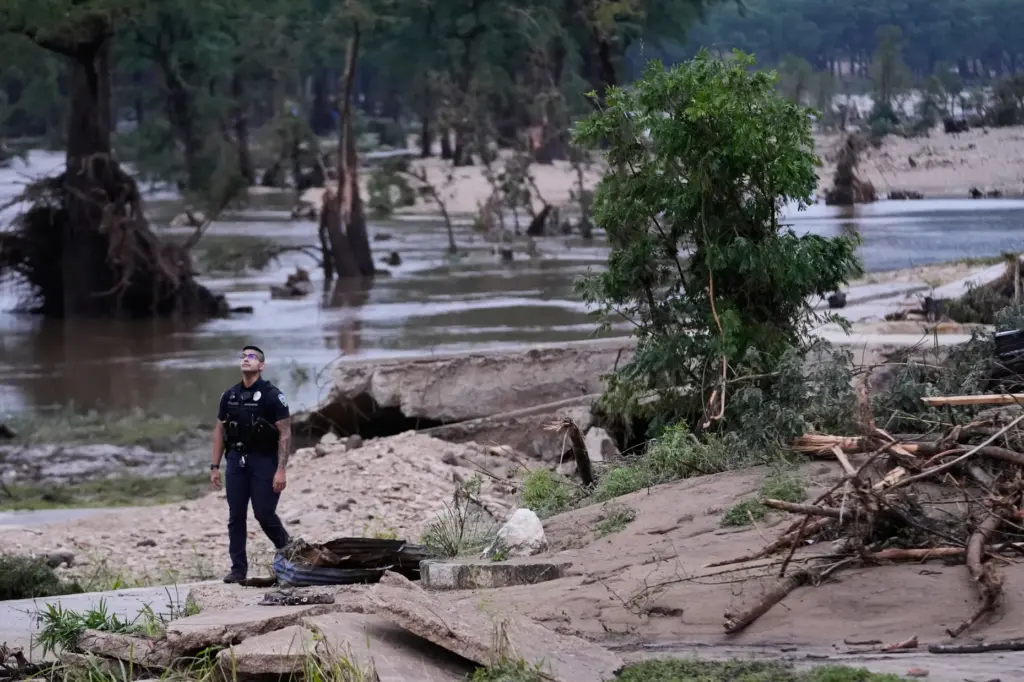 A police officer walks along the Guadalupe River after a...
