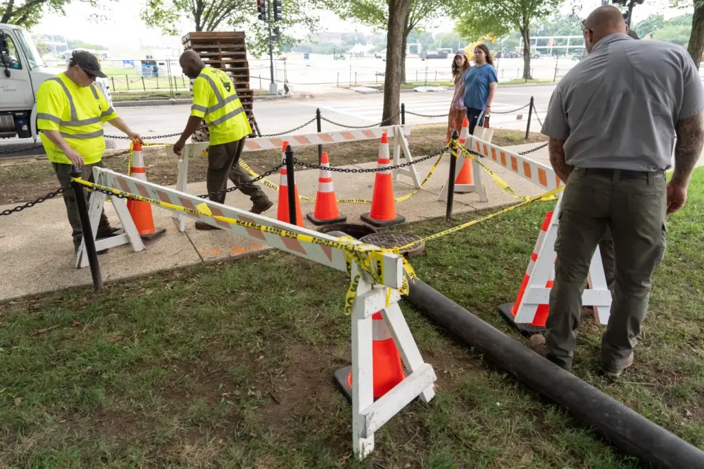 National Park Service workers adjust barricades around a manhole near...