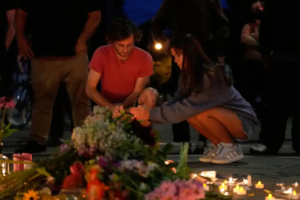 Attendees light candles at a candlelight vigil where a Madison...