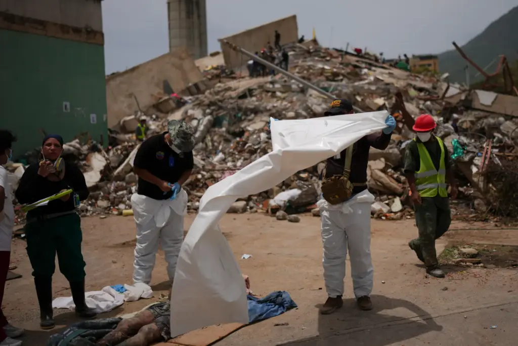 Forensic technicians cover the bodies of earthquake victims in La...