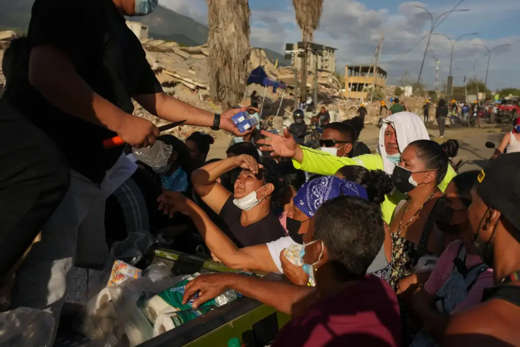FILE – People affected by the earthquakes line up for...