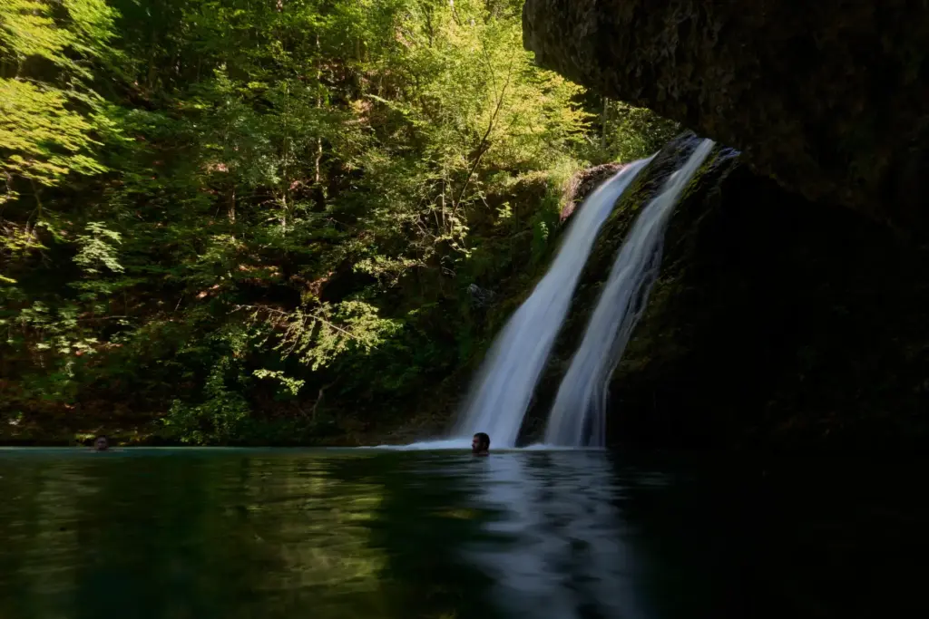 People swim beneath a waterfall in the Enipeas Gorge on...