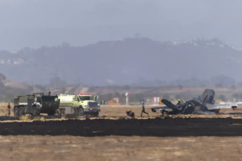 Crews work to douse a F-35 fighter jet that crashed...