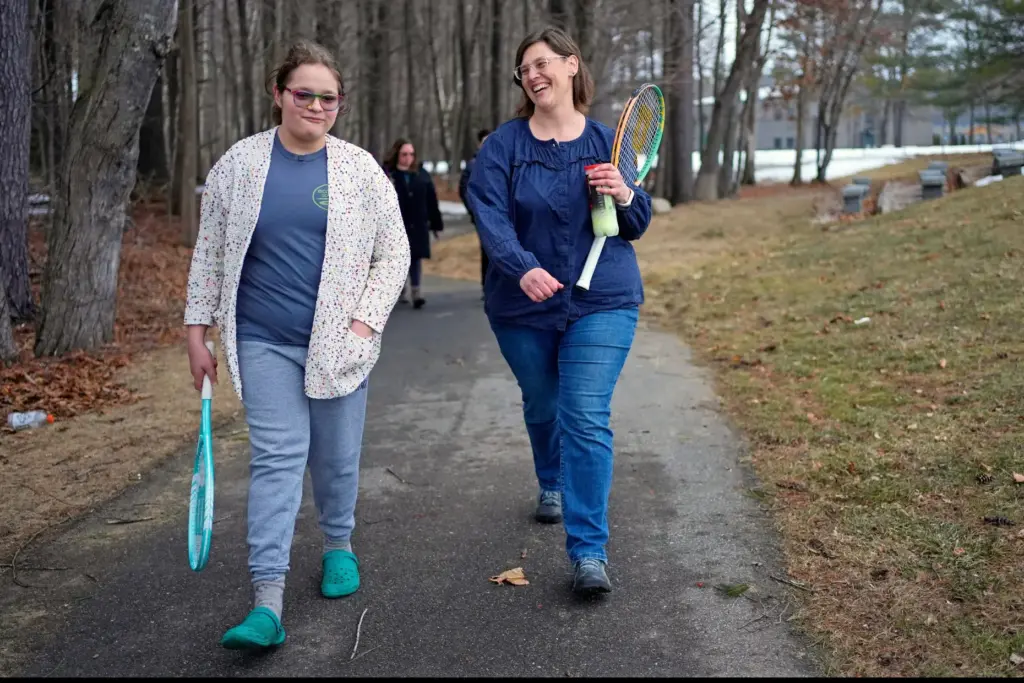 Iris Turmelle walks with her mom, Amy Manzelli, near her high school's tennis courts.