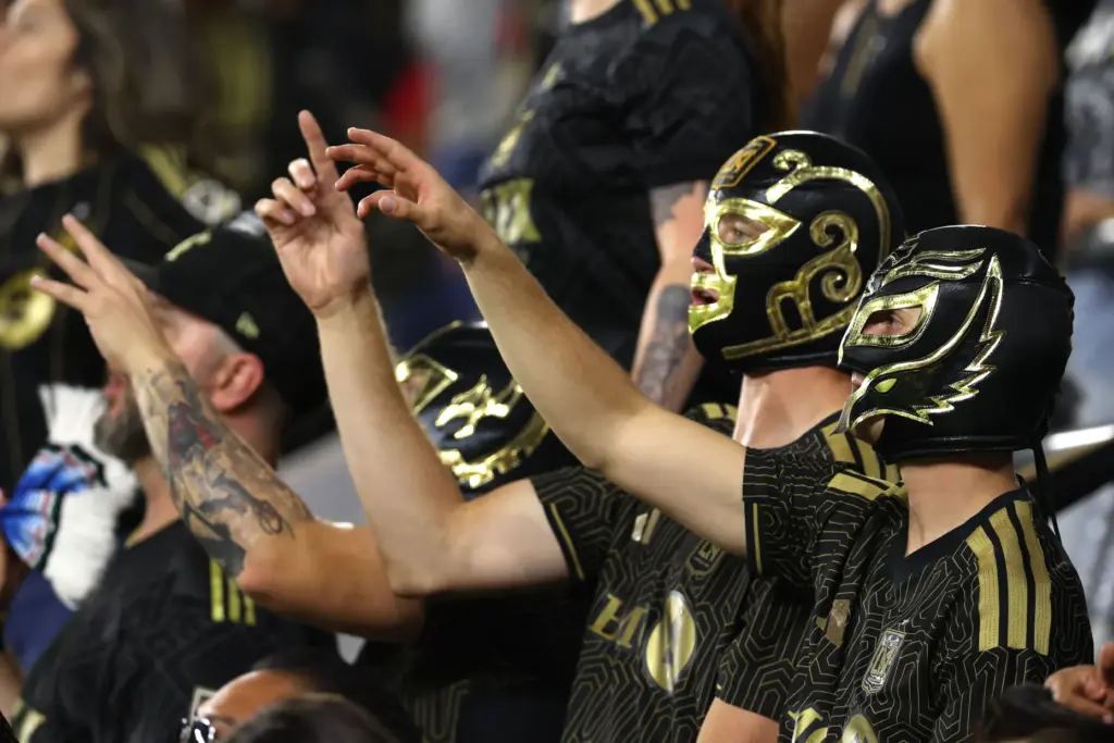 A group of masked Los Angeles FC fans cheer during...