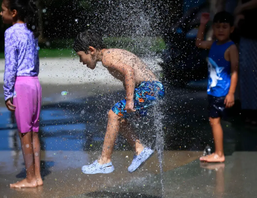 A boy runs in. and out of a water spout...