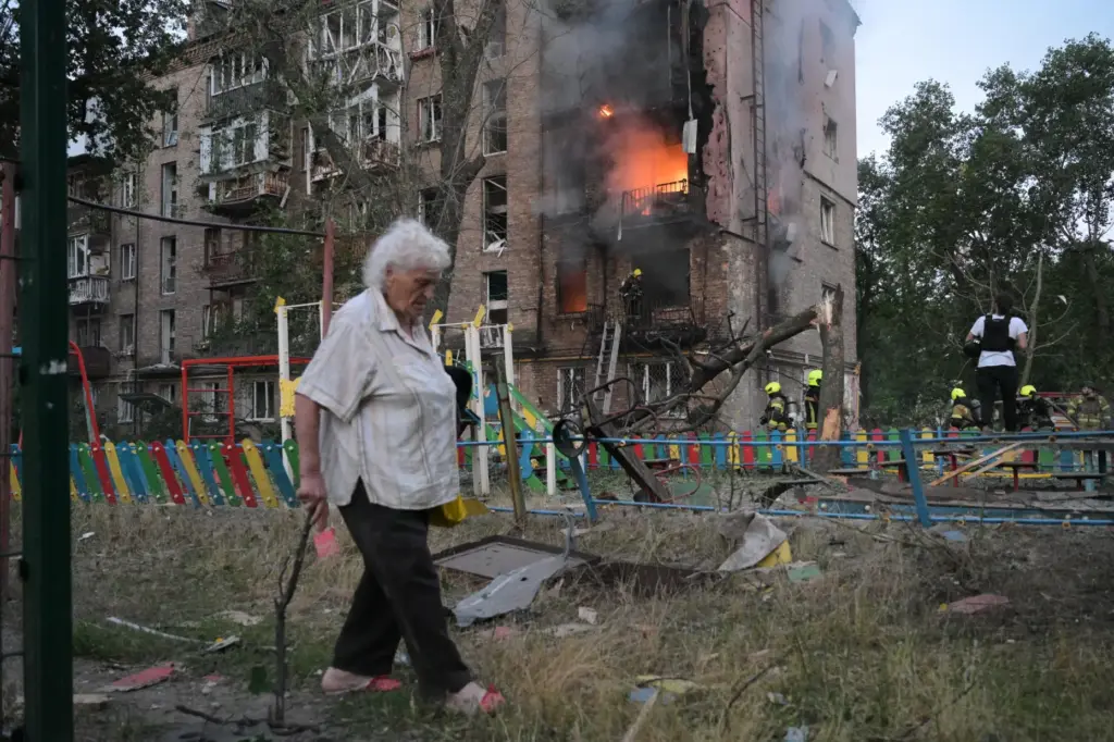 A woman walks past a burning apartment building after a Russian missile attack.