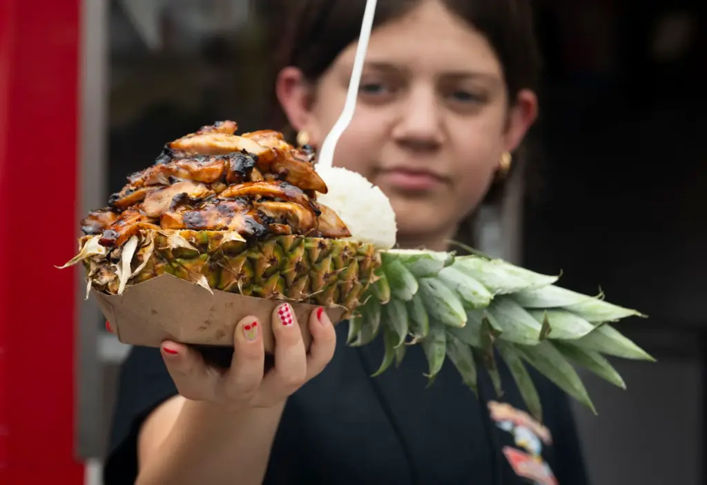 A server holds up Maui Chicken in a pineapple bowl...