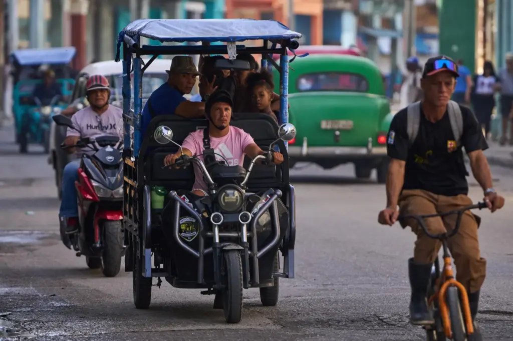 People ride in an electric tricycle in Havana, Cuba, Friday,...