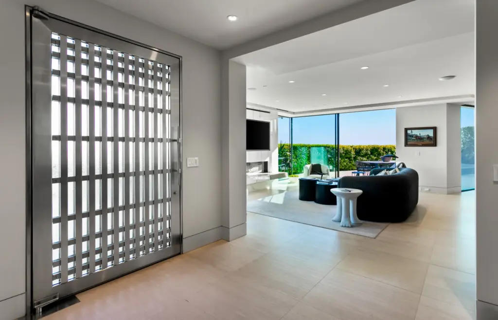 The home’s large stainless-steel door opens into the main living...